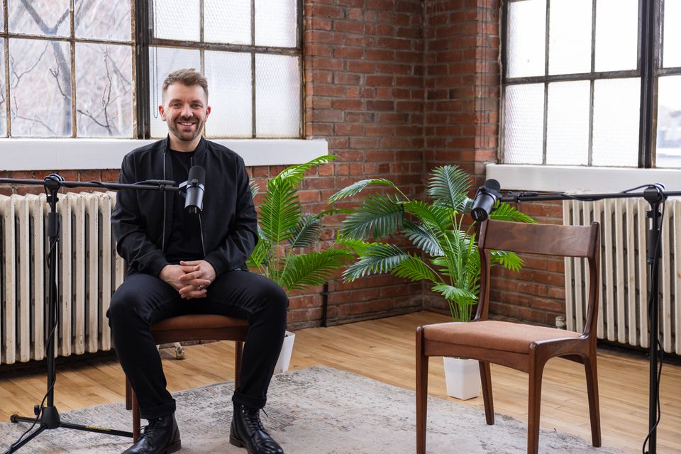 Guest seated at a microphone in a brick loft with plants