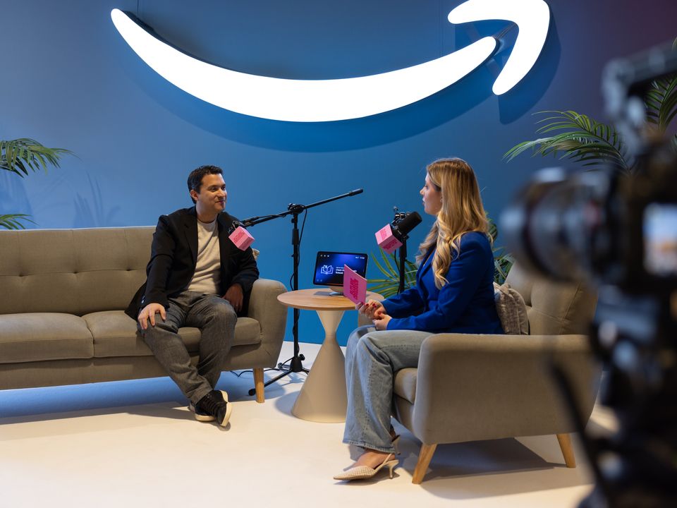 Host and guest on a sofa in front of a large illuminated wall
